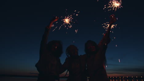 friends celebrating at night with sparklers by the water