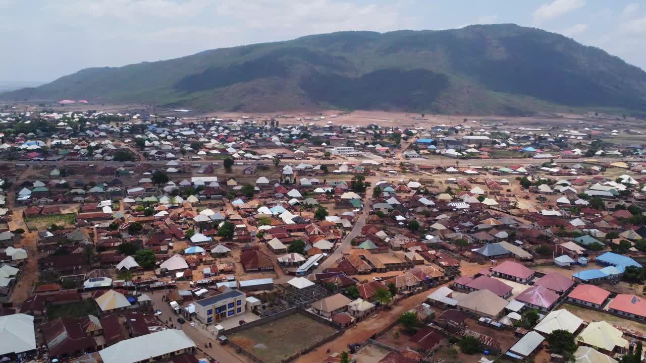 Beautiful high angle pan of a large town in rural Nigeria. Large mountains can be seen in the background of a stunning African landscape