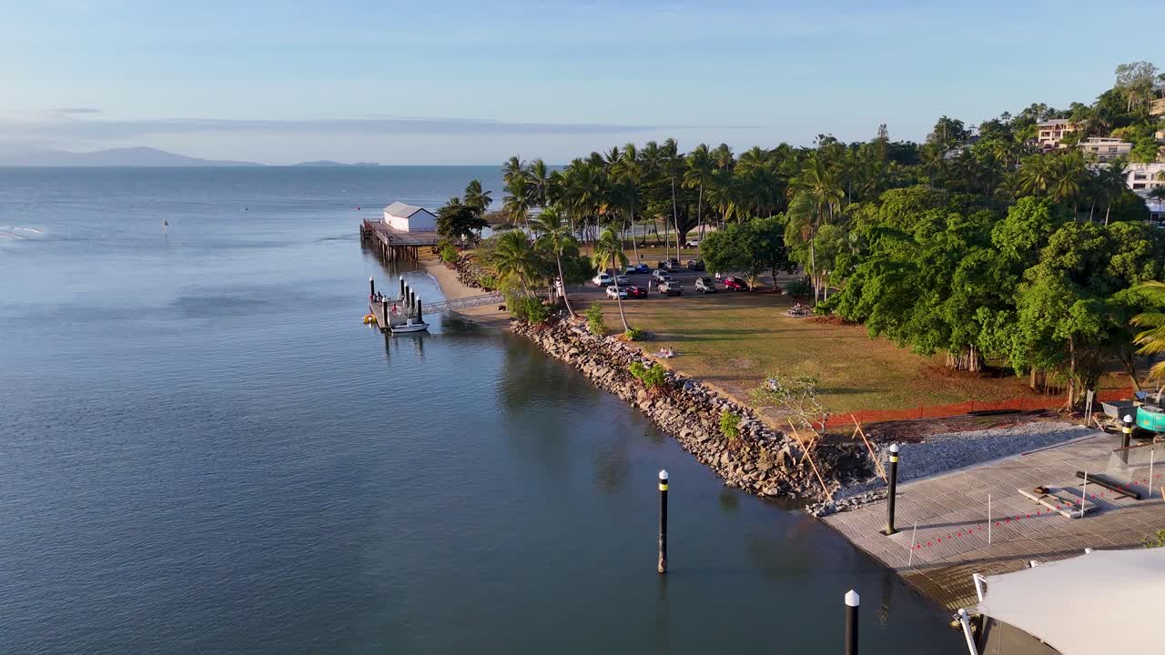 Drone captures tranquil marina, palm trees, and calm ocean waters