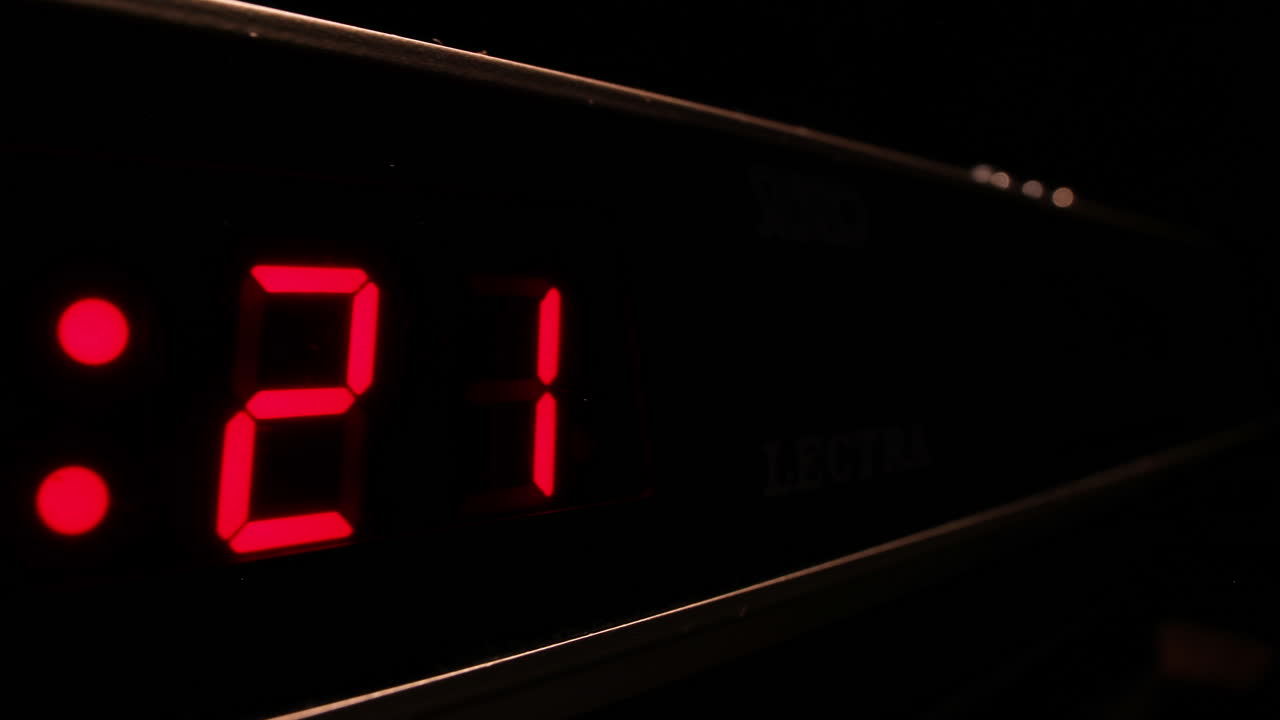 Red digital display clock counting down to midnight in 24-hour time, timelapse