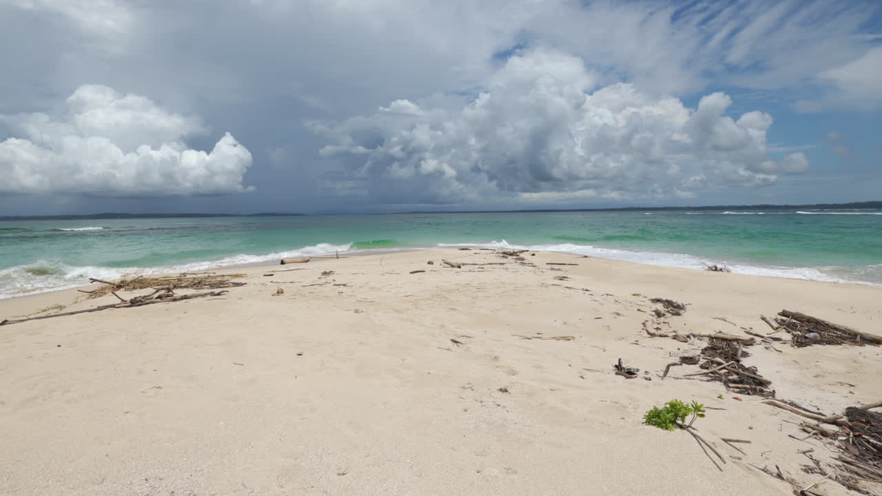 toma manual estática de las olas del agua turquesa en una playa paradisíaca con nubes lluviosas en el fondo
