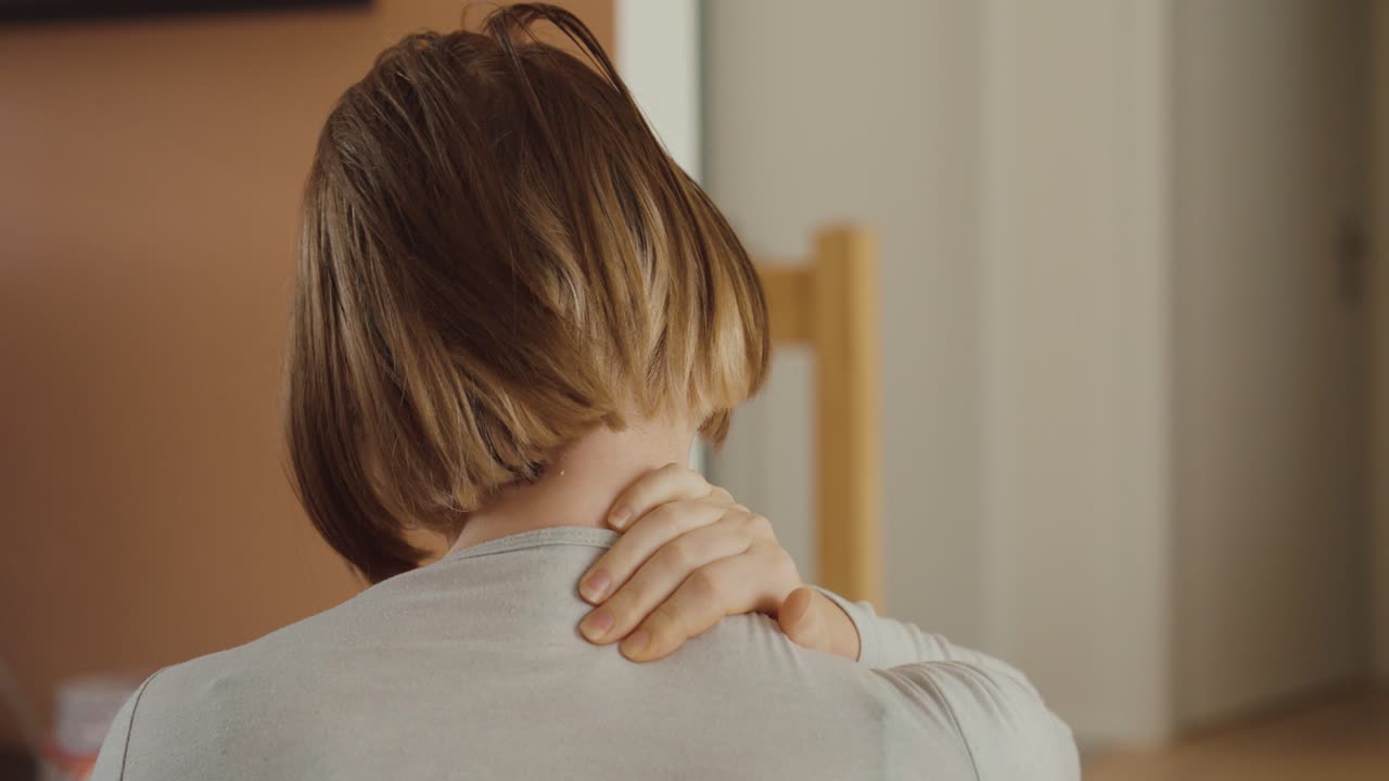 Donna stanca che soffre di dolori cervicali a casa, si massaggia il collo a causa di una postura scorretta o di una posizione sbagliata durante il sonno