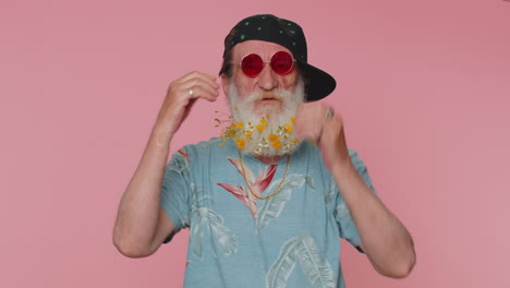 Cheerful-happy-stylish-senior-flowered-beard-man-wearing-sunglasses,-charming-smile-on-pink-wall