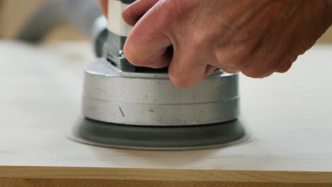 close up of professional carpenter grinding wooden plank in a workshop of a wood factory.