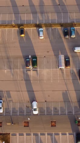 sunset light over parking lot in riga with orderly car rows, vertical overview, cars drive perpendicular