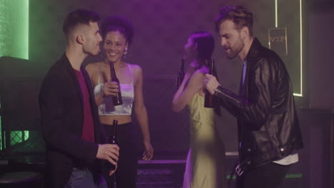 grupo de cuatro jóvenes amigos bebiendo cerveza y bailando en la discoteca 1