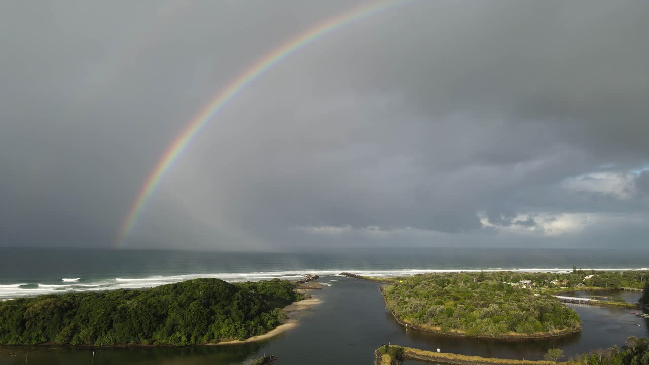gran arco iris colorido ubicado en la pintoresca ensenada de un río costero cerca de un popular lugar de vacaciones.
