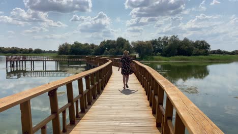 girl in flower dress walking on wooden walkway over tablas de daimiel marshes landscape