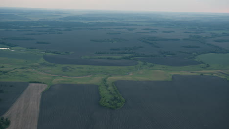 aerial top down view of vast mosaic of cultivated fields and meandering river channels stretching to distant horizon under soft pastel sky at dusk creating tranquil serene rural panorama