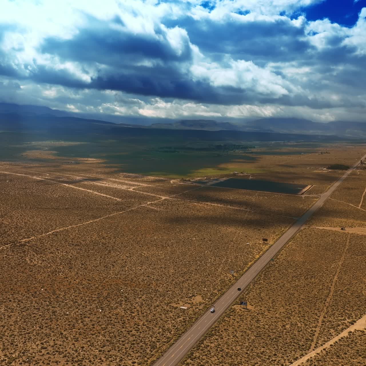 Vast desert crossed by highways and roads. Thick cloudscape covering the landscape from the sun. Aerial view