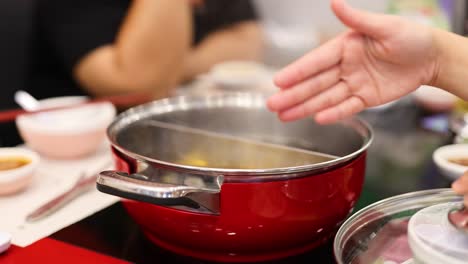 hands preparing hotpot soup at a table