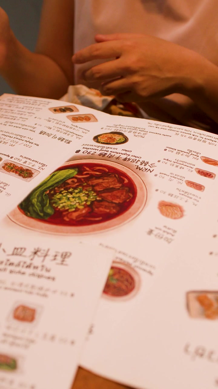 Woman uses a mobile phone while seated at a dining table with menus.