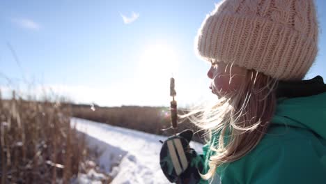 cute little girl learning to blow on cat tail on winter nature walk sunny slomo