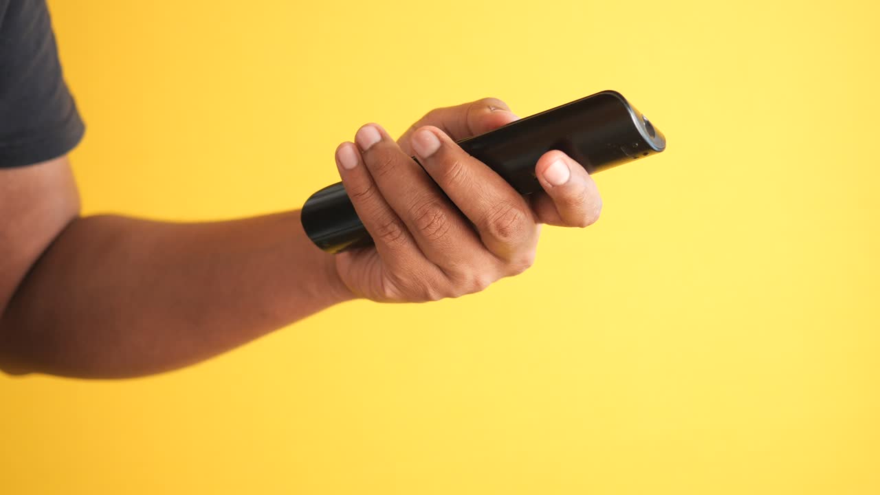 검은색 tv 리모컨을 들고 있는 손