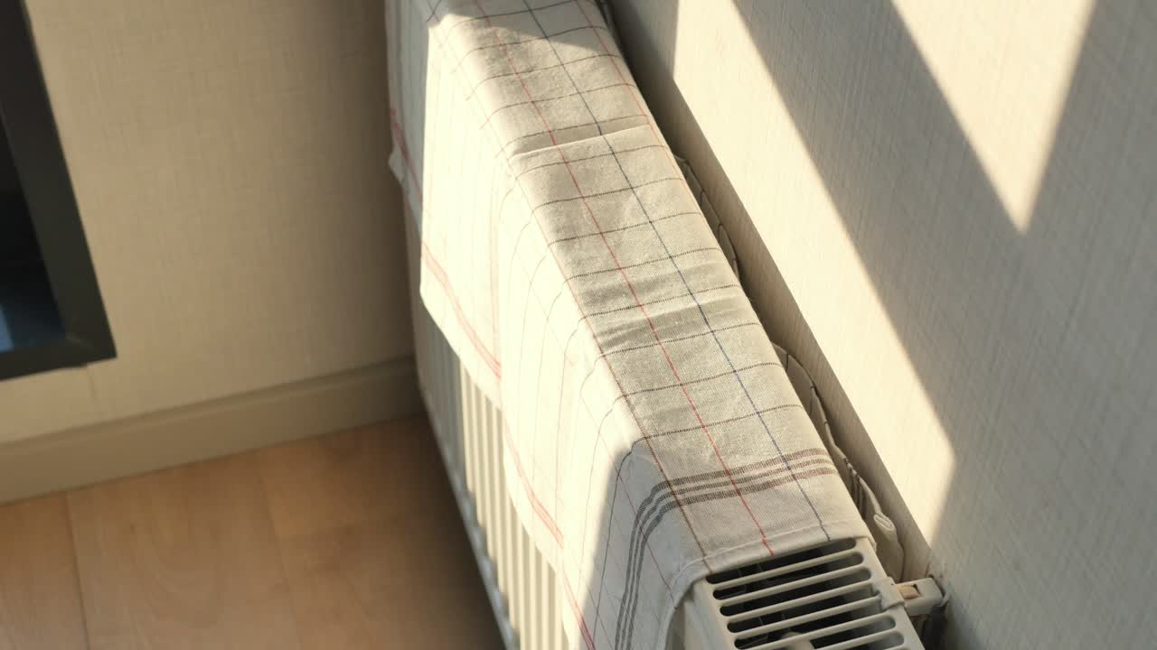 Radiator covered with a checked towel, sunlight