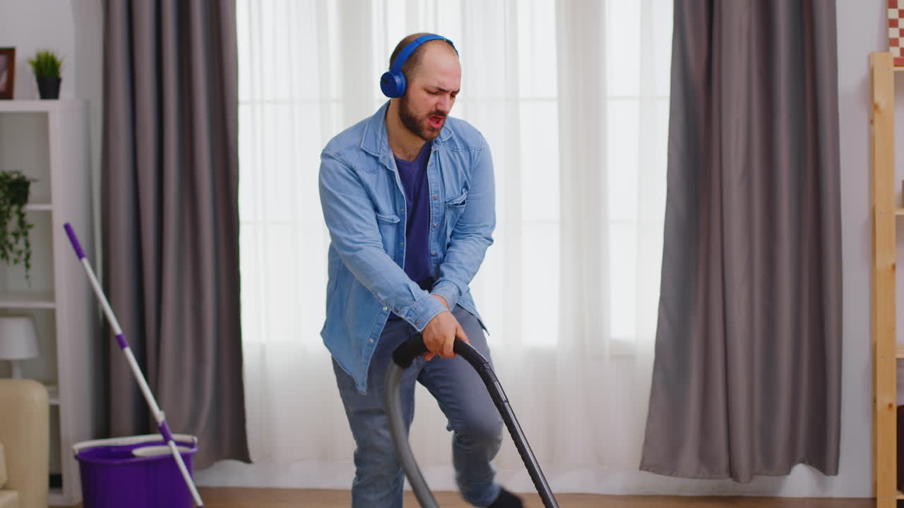 hombre con auriculares durante la limpieza de la casa
