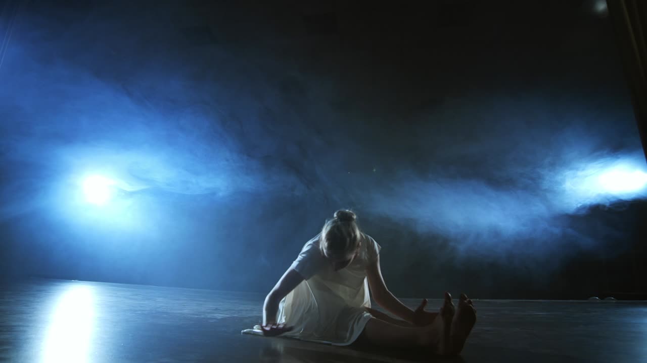 Modern ballet dancing woman barefoot lying on the floor doing spins and pirouettes and somersaults