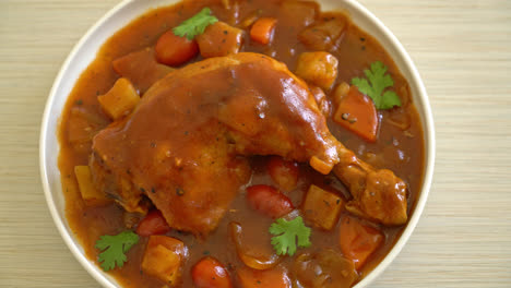 homemade chicken stew with tomatoes, onions, carrot and potatoes on plate with rice