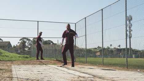 practicing baseball, man in uniform standing near fence on field