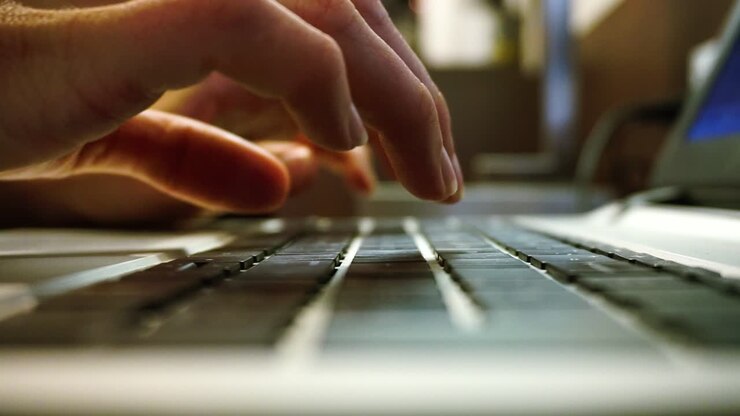 Straight side on footage of womens hands typing on laptop keyboard