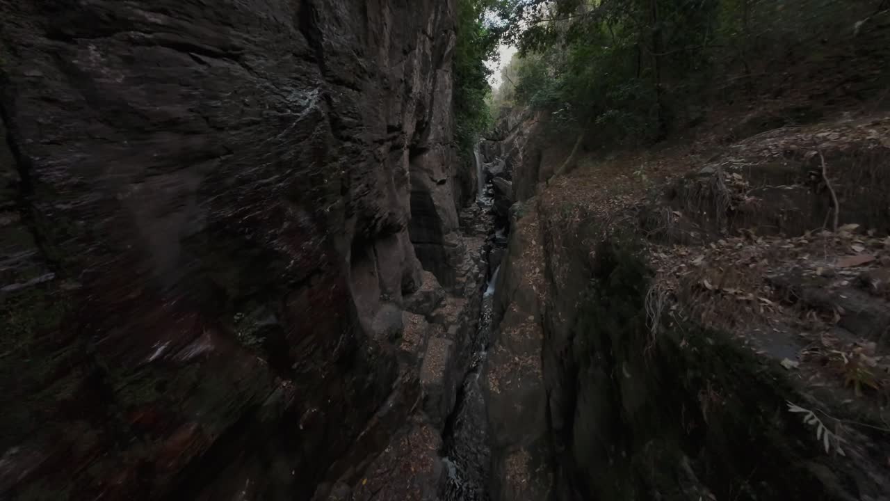 FPV-luftfoto av Kenios fra elven Raizama i Chapada dos Veadeiros, som flyter gjennom en steinete canyon med frodig vegetasjon i Sao Miguel, Brasil