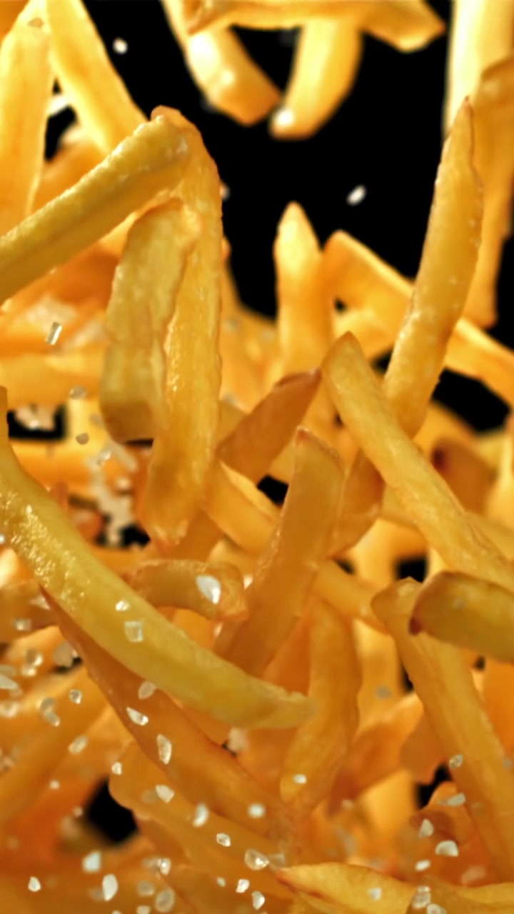 Gyllene pommes frites och salt som faller i slow motion