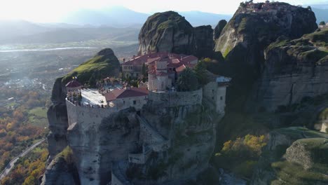 El-Monasterio-De-Meteora-De-4k-De-Varlaam-Se-Eleva-A-Vista-De-Pájaro:-El-Gran-Meteorito-En-La-Distancia,-Monasterio-En-Una-Montaña,-Paisaje:-Dron-Aéreo,-Μετέωρα,-Ελληνικά,-Antigua-Grecia,-Cine,-Dios