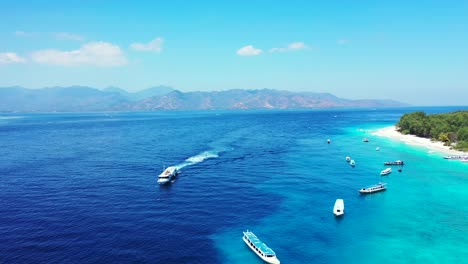 Touring-boats-sailing-on-blue-sea-near-turquoise-lagoon-of-tropical-island-with-resorts-for-vacationers-and-exotic-beaches-on-a-sunny-day-with-bright-sky