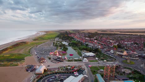 Von-Oben-Zeigen-Videoaufnahmen-Eine-Atemberaubende-Sonnenuntergangsszene-über-Skegness,-Einer-Malerischen-Küstenstadt-Im-Vereinigten-Königreich,-Mit-Der-Stadt-Selbst,-Der-Promenade,-Dem-Pier-Und-Der-Küste