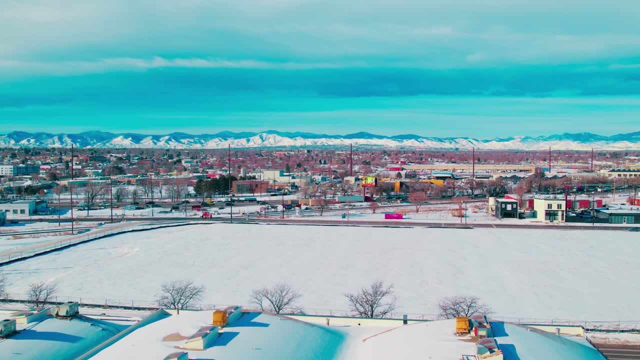 Winter panorama of Denver, Colorado, featuring a frosty urban skyline with the dramatic snow-capped Rockies in the background.