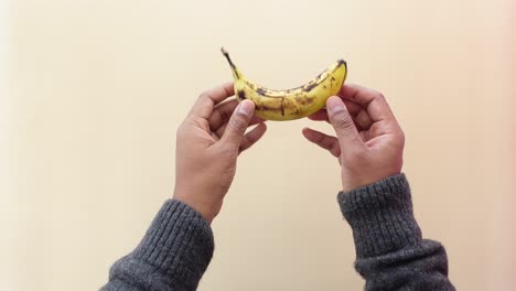 a man's hands holding a ripe banana