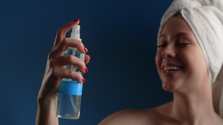 Woman applying face mist after shower