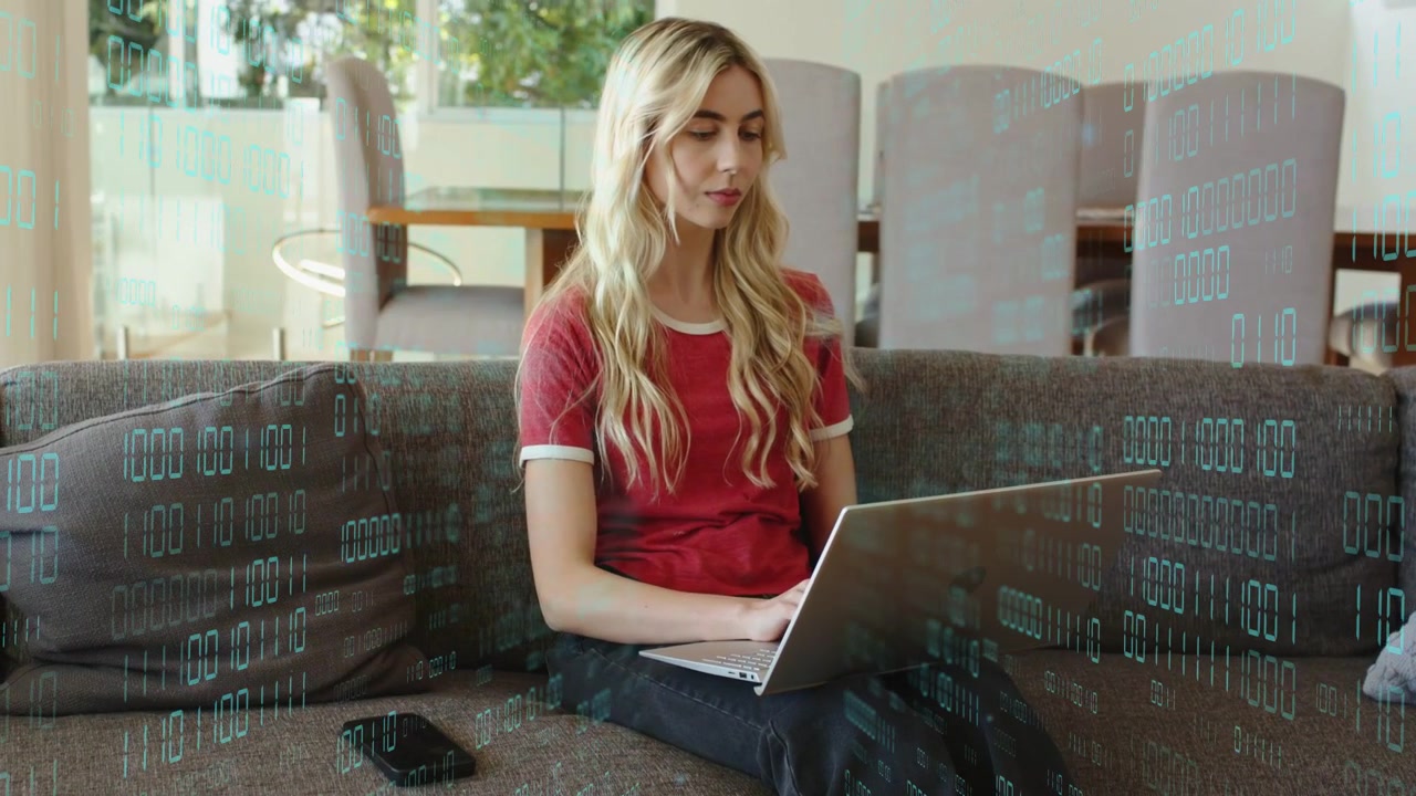 Adult woman on sofa starting typing on laptop, binary digits flowing across device, analyzing data