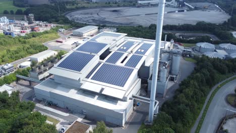 Instalación-Solar-Limpia-En-La-Azotea-En-La-Vista-Aérea-De-Un-Edificio-De-Oficinas-Moderno-Con-Una-Central-Eléctrica-De-Carbón-En-El-Fondo-Que-Aumenta-Lentamente-Hacia-Adelante