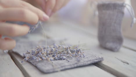 Female-hand-puts-a-bouquet-of-lavender-on-a-wooden-table