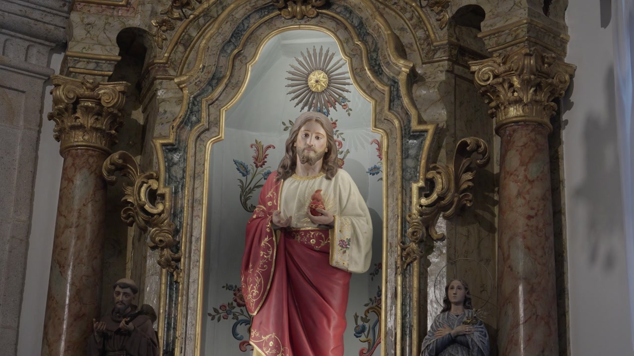 Close-up of a religious sculpture of Jesus Christ inside a historic chapel with gold carvings and marble pillars.