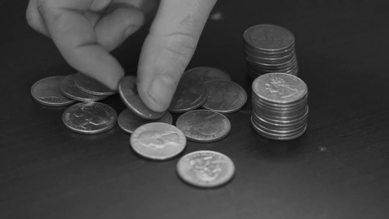 Black and White clip of counting spare change - USD quarters.