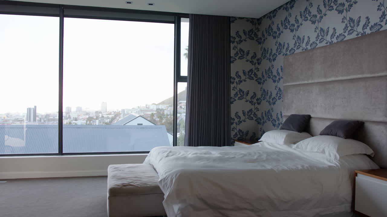 Modern bedroom with large window, white bedding, and cityscape view, at home