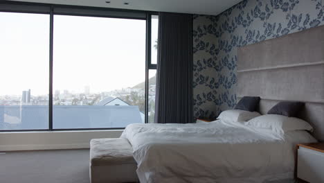 modern bedroom with large window, white bedding, and cityscape view, at home