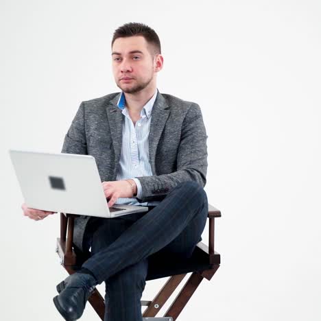 portrait of serious businessman with a laptop. thoughtful young man sitting in a chair and working a laptop isolated on white background.