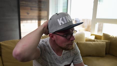 El-Hombre-Viendo-La-Televisión-Arregla-Su-Gorra-De-Béisbol,-Zoom-En-Cámara-Lenta