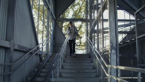 hombre cargando una bicicleta por las escaleras en un entorno urbano