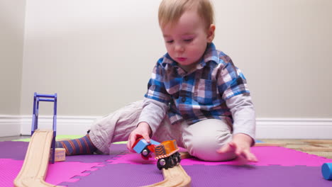 baby boy playing with a wooden toy train set