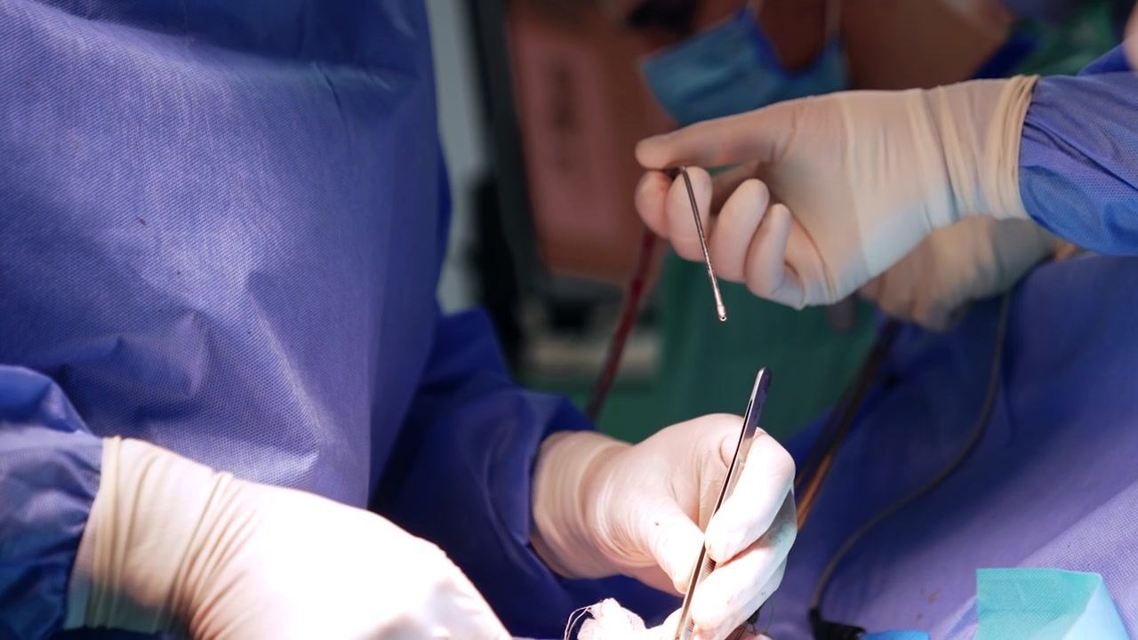 Strumento metallico e filo nelle mani guantate del chirurgo. Utilizzo di strumenti in neurochirurgia. Primo piano