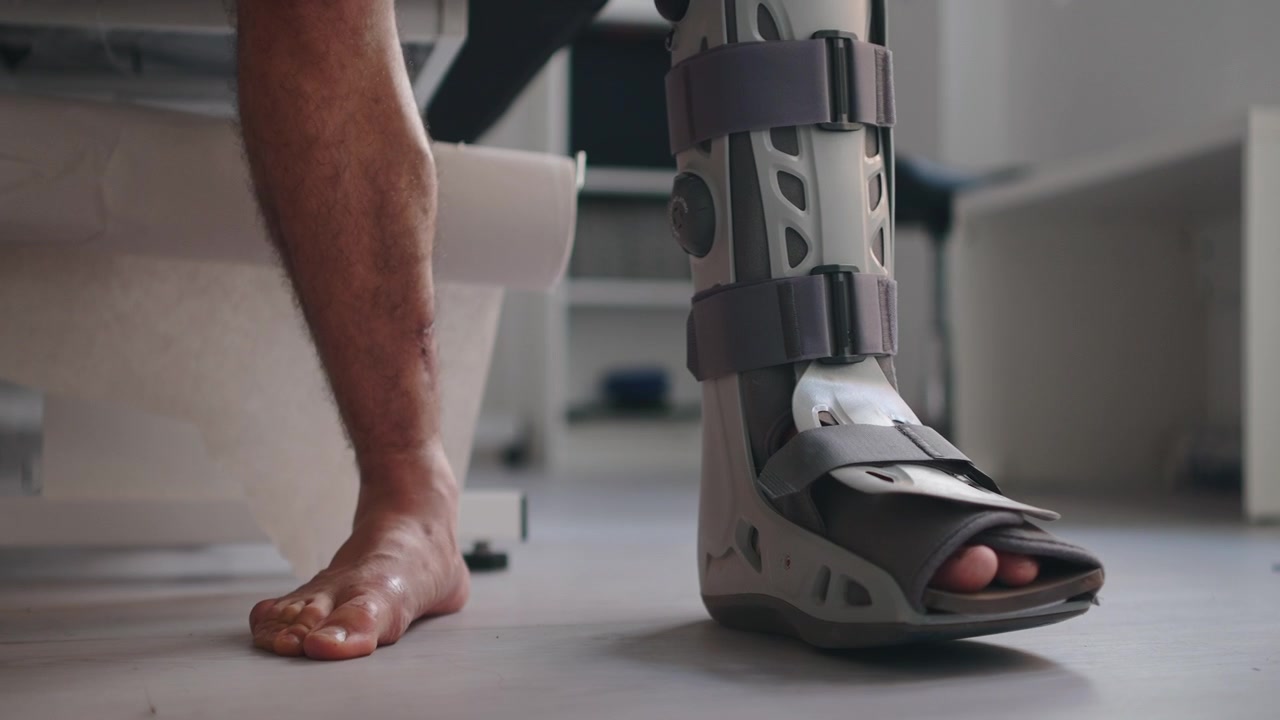 Patient Adjusting Orthopedic Walking Boot on Injured Leg