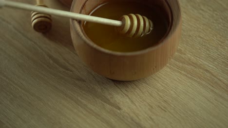 honey dripping, pouring from honey dipper in wooden bowl. close-up. healthy organic thick honey dipping from the wooden honey spoon, closeup. 4k uhd video footage. slow motion