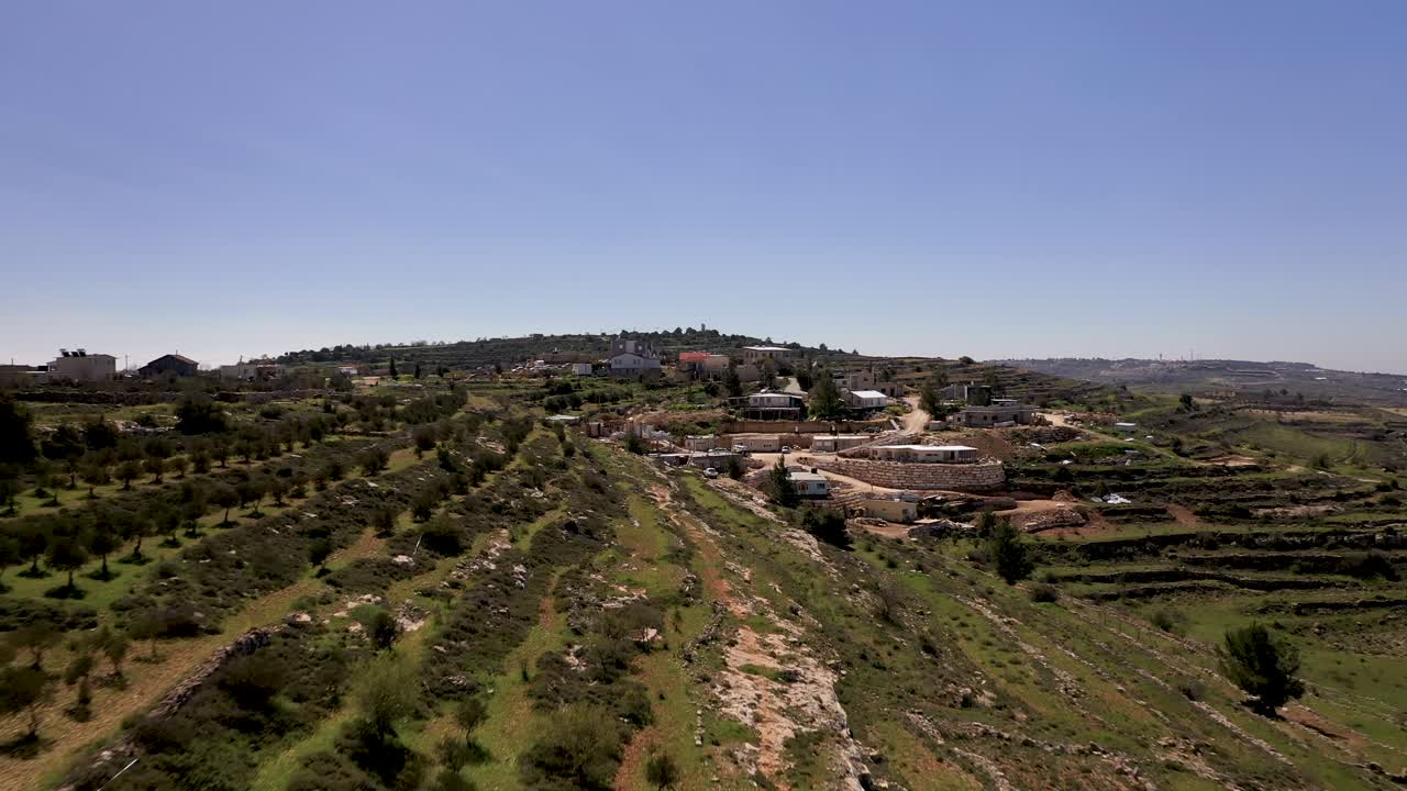 toma aérea de un pequeño pueblo en la ladera de una colina verde en las montañas, hermoso día soleado, filmada con un dron