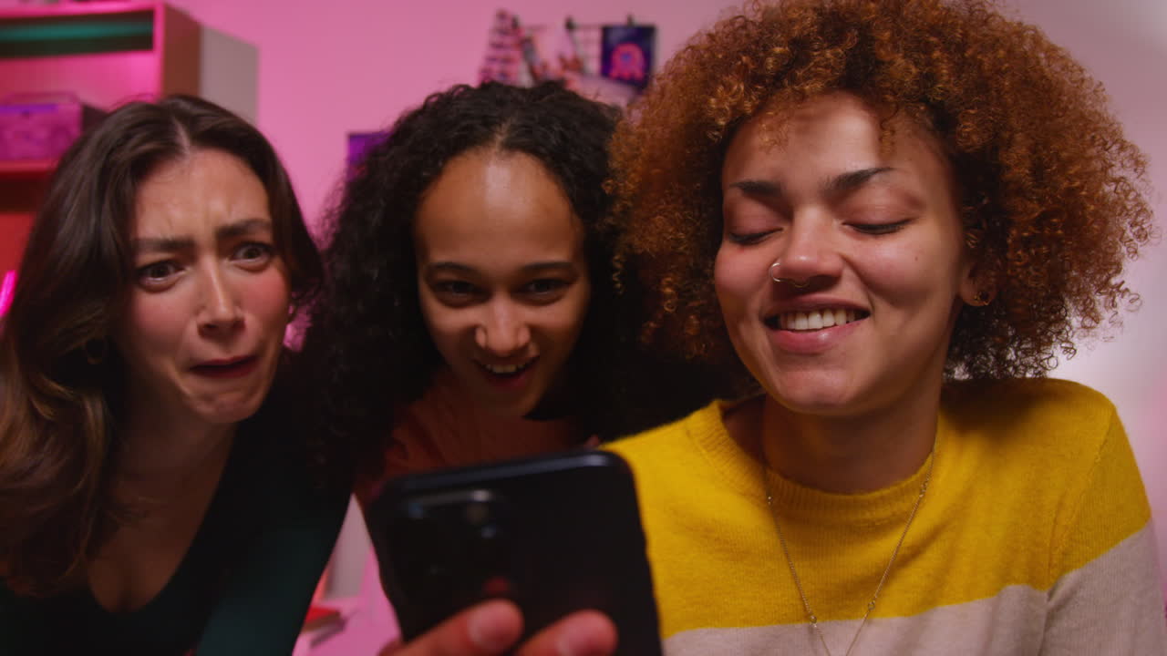 tres amigos mirando un teléfono inteligente
