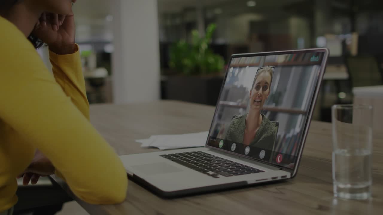 Donna che ascolta un collega parlare; sovrapposizione su un portatile che mostra codice e barra di avanzamento in ambito tecnologico