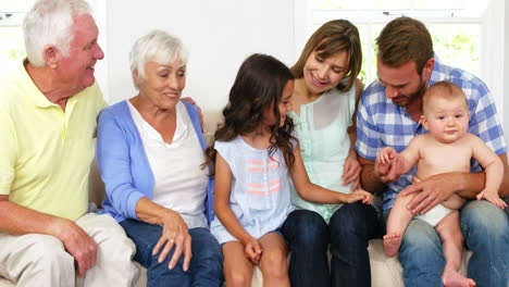 familia linda sentada en un sofá y mirando a un bebé